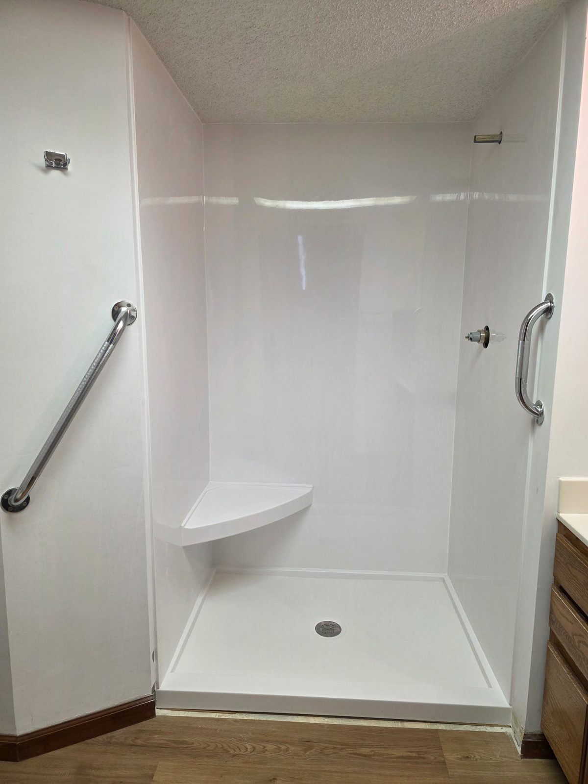 Completed white Onyx Collection solid surface shower with corner seat and low-profile base, installed by Brewer Custom Floors