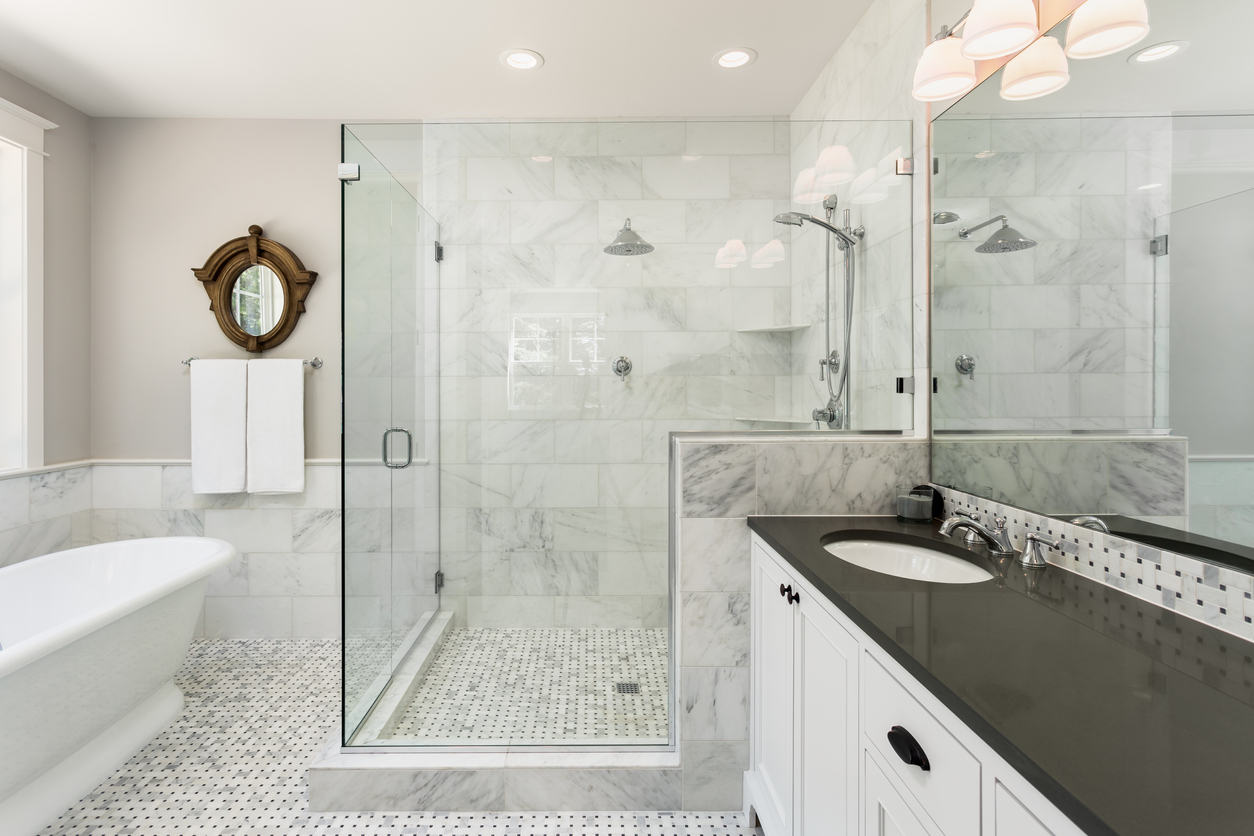 Custom marble tile shower with glass enclosure and basketweave marble floor