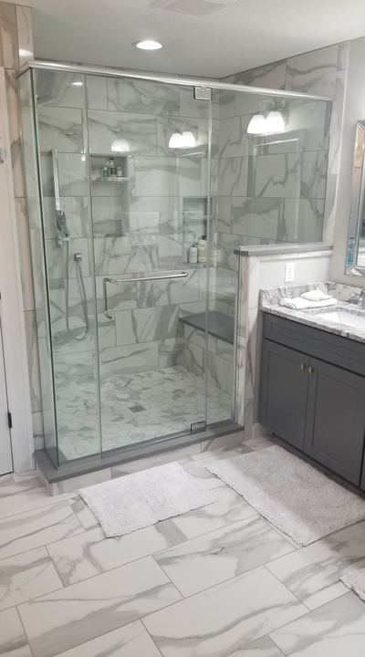 Glass walk-in shower with marble-look tile walls, hex mosaic pan, bench and matching marble porcelain bathroom floor