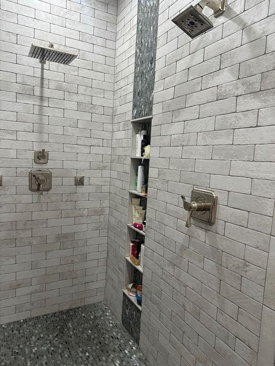 Walk-in shower with white brick-look subway tile, glass mosaic accent stripe, tall shelf niche and dual shower heads