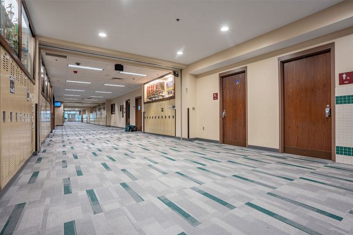 Gray and teal carpet tile in a high school hallway lined with lockers