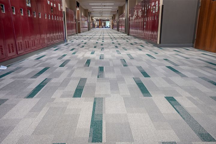Gray and green patterned carpet tile in a high school hallway lined with maroon lockers