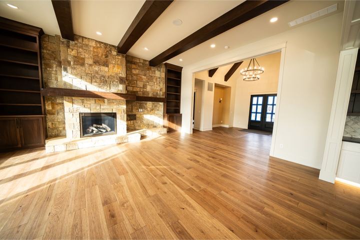 Wide-plank white oak hardwood in a great room with stone fireplace and wood ceiling beams