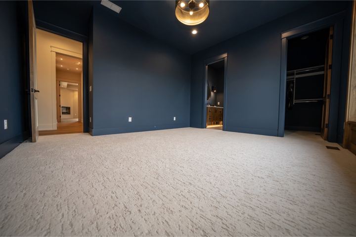 Textured cream carpet in a navy-walled master bedroom with walk-in closet