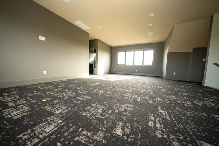 Bonus room with charcoal and cream abstract patterned carpet and large sunny window