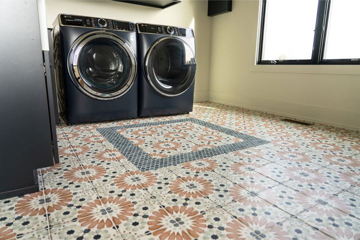 Laundry room with colorful Moroccan-pattern tile floor and inset border rug design under navy washer and dryer