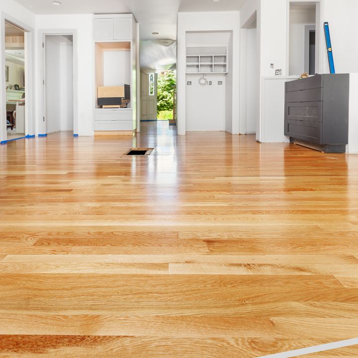 Freshly finished light red oak hardwood flooring running through an open hallway and entry