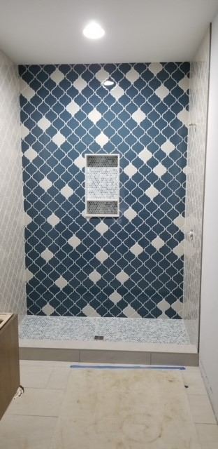 Tiled shower with blue and white arabesque accent wall, penny tile niche and mosaic shower pan