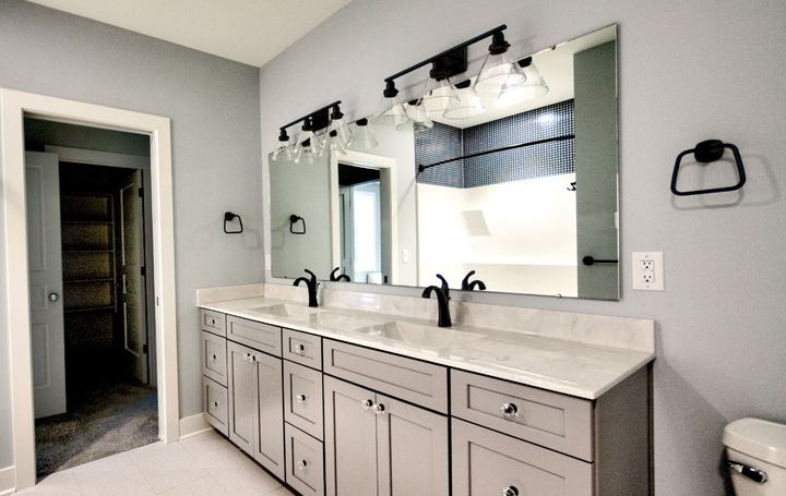 Jack-and-Jill bathroom with light tile floor, gray double vanity, marble top and navy mosaic shower accent