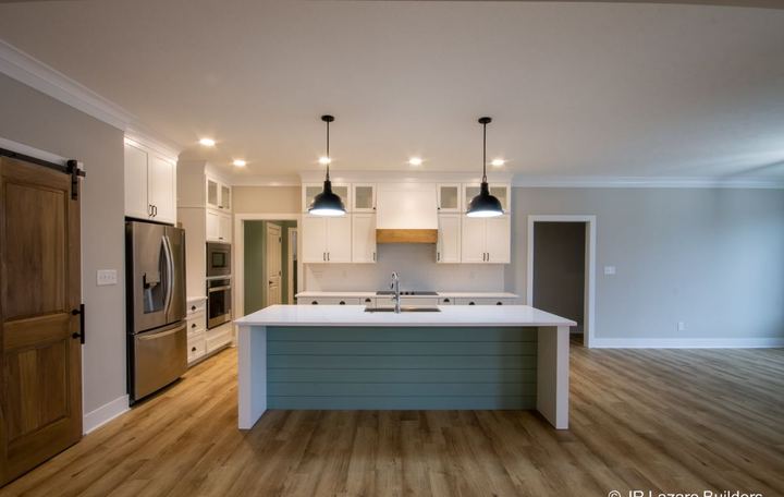Light luxury vinyl plank flooring in an open kitchen with teal shiplap island and picket tile backsplash