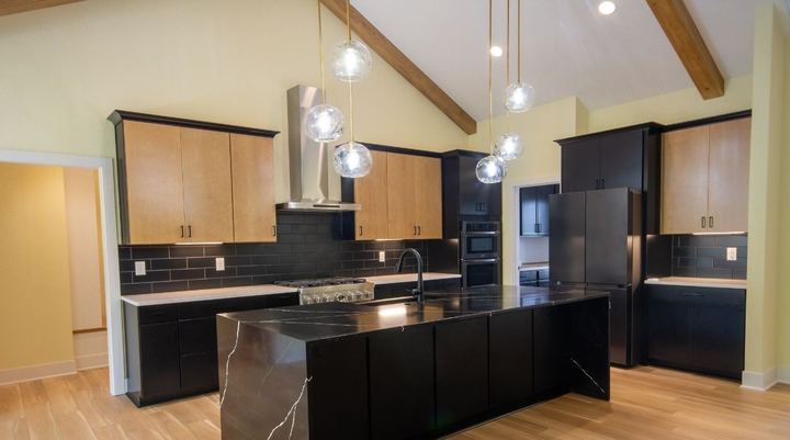 Kitchen with black subway tile backsplash, waterfall quartz island and wood-look plank flooring