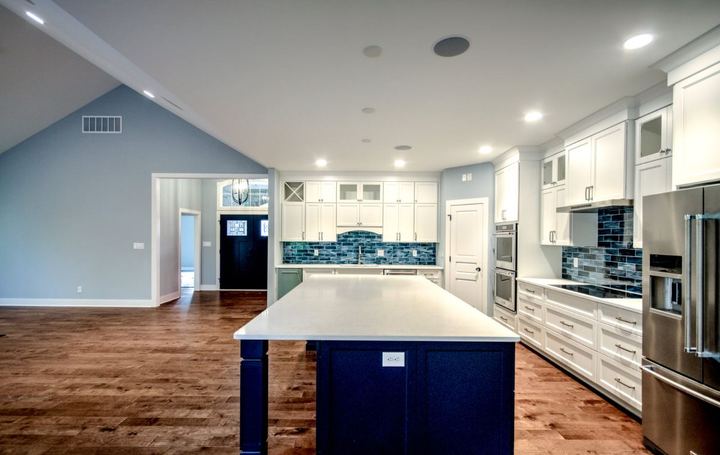 White kitchen with deep blue glass subway backsplash, navy island and hand-scraped hardwood floors