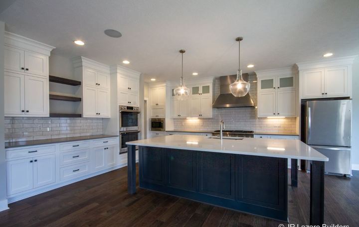 White kitchen with Carrara-look subway backsplash, navy island and dark hickory hardwood floors