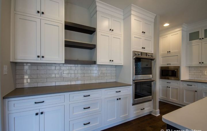 White kitchen with polished marble subway tile backsplash, floating shelves and dark hardwood floor