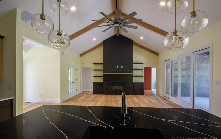Vaulted great room with black tile fireplace surround and wood-look plank flooring