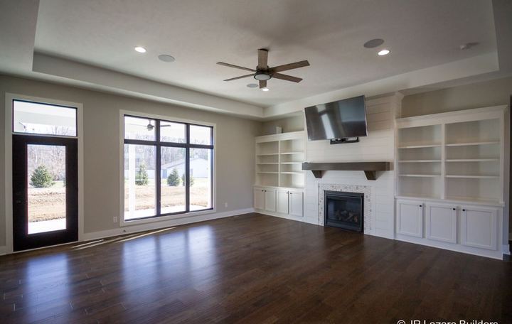 Living room with dark hand-scraped hardwood plank flooring, shiplap fireplace with mosaic surround and built-ins