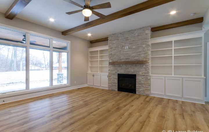 Light oak-look plank flooring in a living room with stacked stone fireplace and built-in shelving