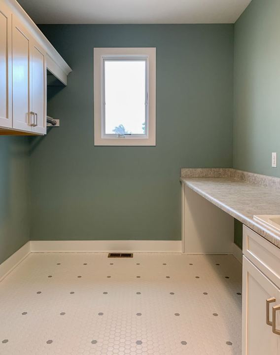 Laundry room with white hexagon mosaic tile floor accented by gray dots and sage green walls