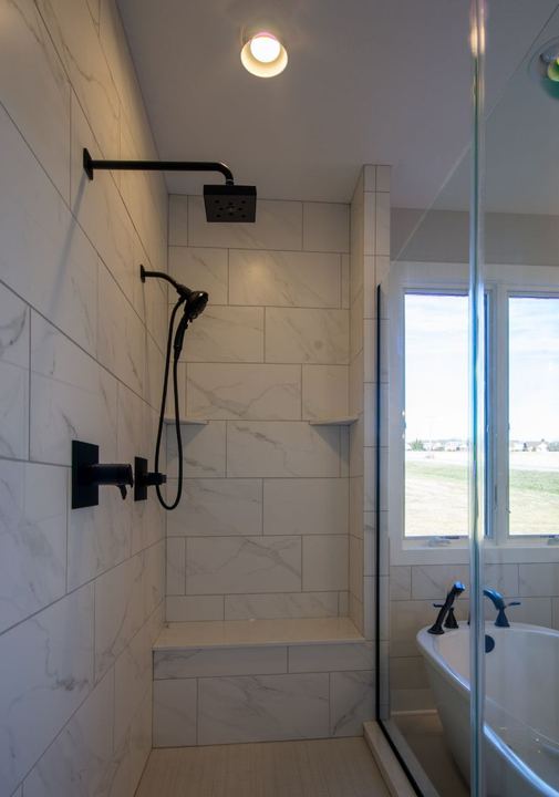 Walk-in shower with Calacatta marble-look tile, matte black fixtures, bench seat and freestanding tub beyond