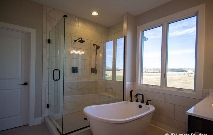 Master bath with calacatta-look tile corner shower, freestanding tub, tile wainscot and black fixtures