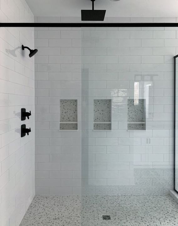 Walk-in shower with white subway tile, three mosaic-lined niches, penny tile floor and matte black fixtures