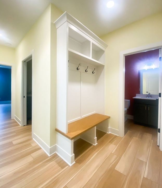 Wood-look plank tile flooring in a mudroom hall with built-in bench and coat hooks