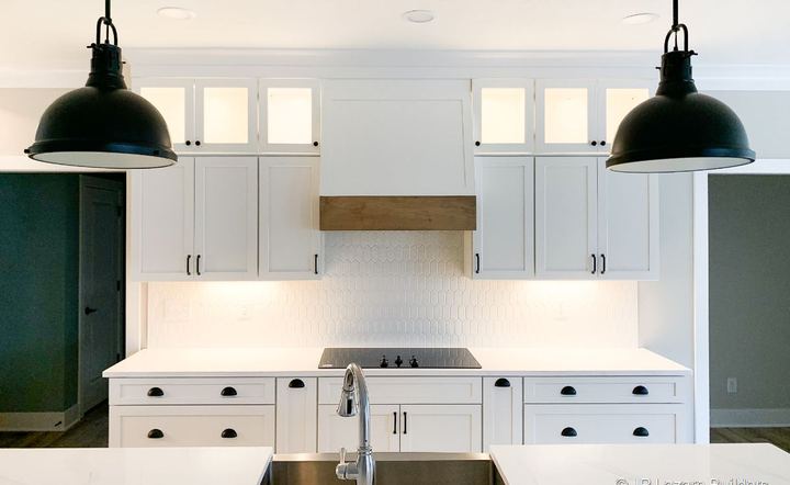 White farmhouse kitchen with elongated picket mosaic tile backsplash and black pendant lights