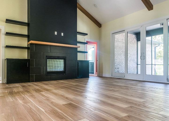 Living room with black tile fireplace, floating shelves and light wood-look plank flooring