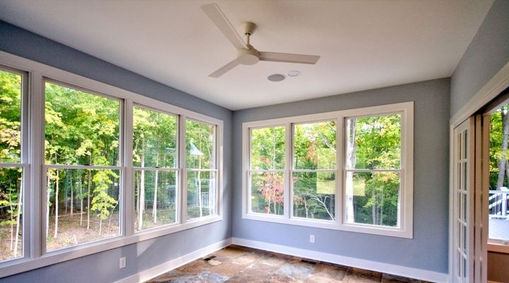 Sunroom with rust and gray slate-look tile floor, blue walls and wooded window views