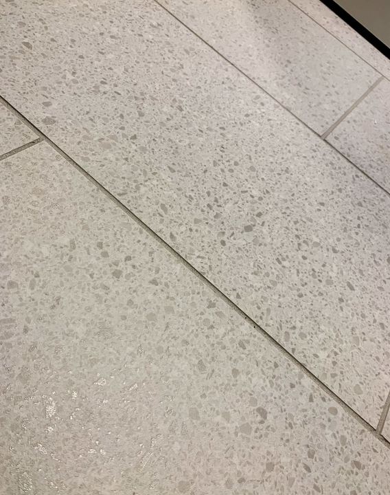 Close-up of terrazzo-look porcelain floor tile in soft gray with speckled aggregate pattern