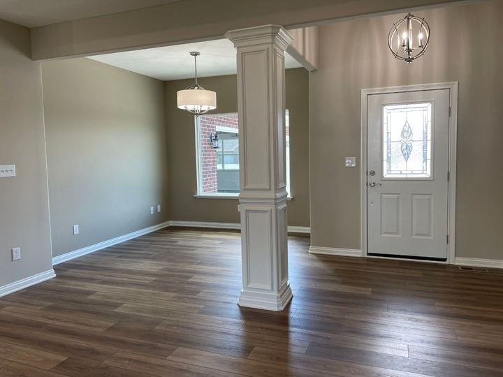 Warm brown luxury vinyl plank flooring in an entryway and dining room with white column detail