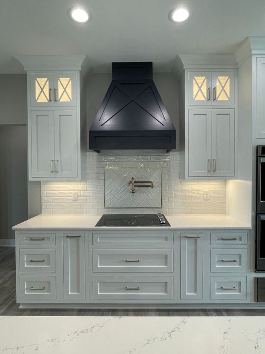 White kitchen with beveled subway backsplash, gold-framed herringbone accent panel and navy range hood