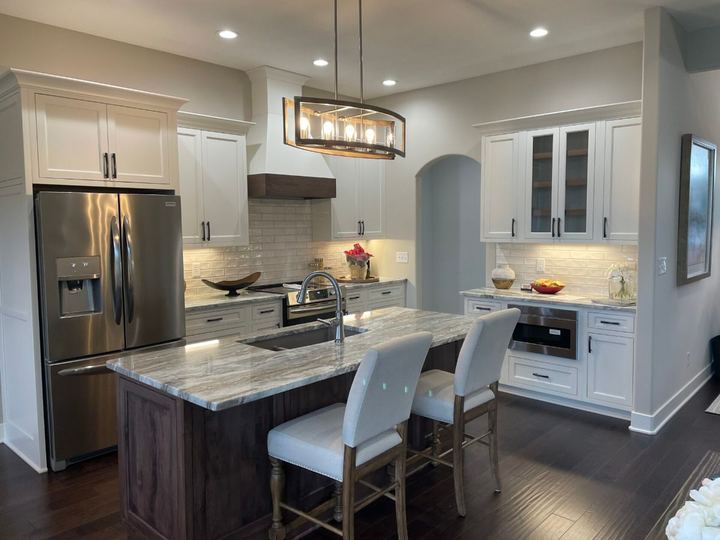 Kitchen with cream beveled subway tile backsplash, granite island and dark hardwood flooring