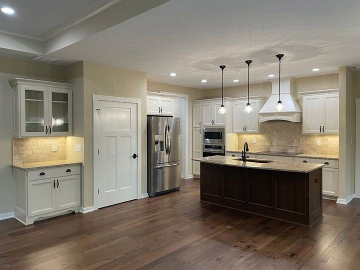 Kitchen with tumbled travertine backsplash, cream cabinets and dark hickory hardwood floors