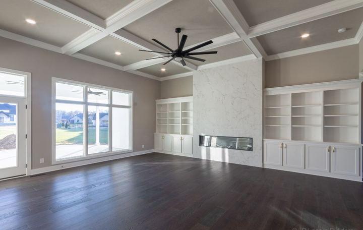 Living room with floor-to-ceiling marble-look tile fireplace surround, built-ins and dark hardwood floors