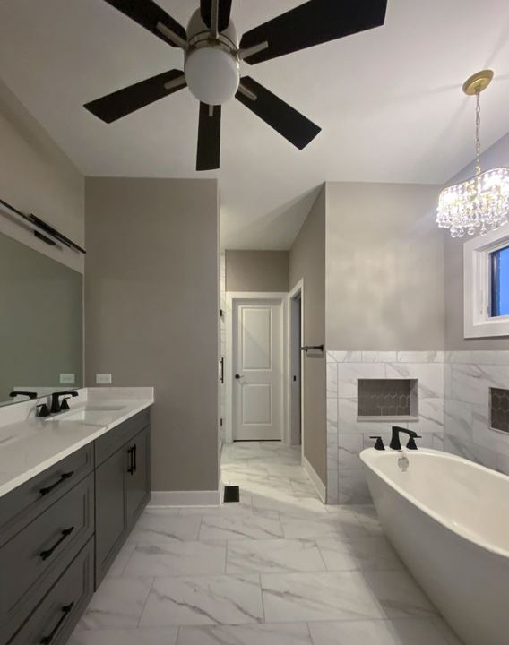 Master bath with marble-look tile floor and wainscot, hex-tile niches, freestanding tub and gray vanity