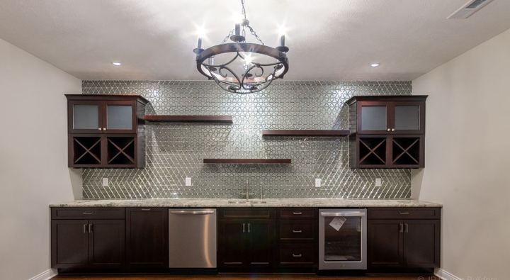 Basement wet bar with full-height glass triangle mosaic backsplash, dark cabinets and hardwood floor