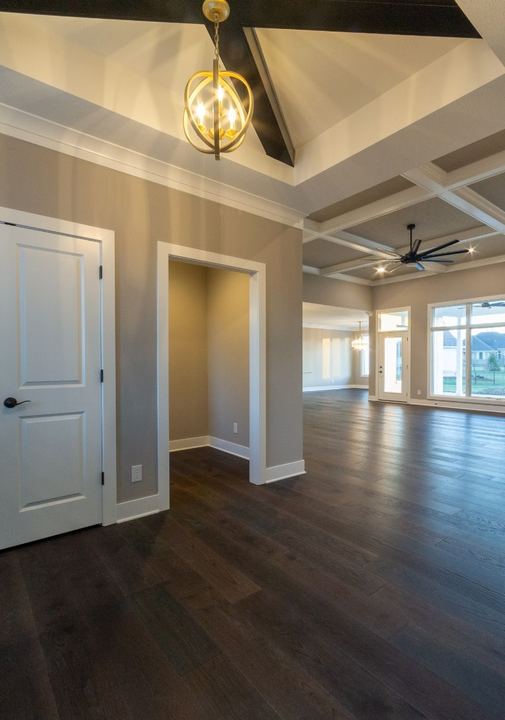 Open floor plan with dark hand-scraped hardwood flooring, coffered ceilings and gold orb chandelier