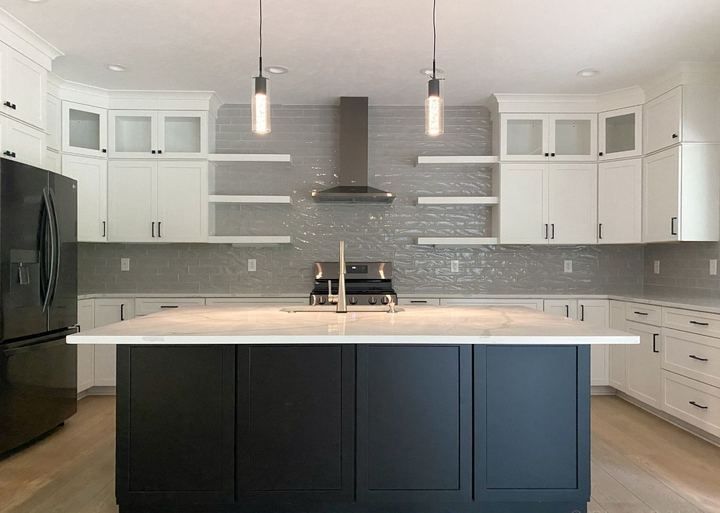 Glossy gray subway backsplash run to the ceiling in a white kitchen with black island and quartz top