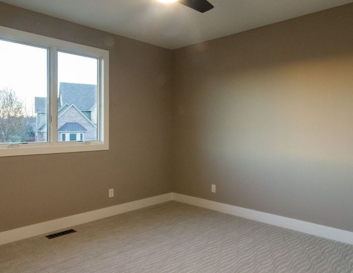 Bedroom with beige wave-textured patterned carpet and taupe walls