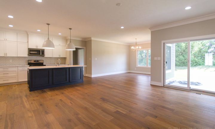 Wide-plank hardwood flooring through an open-concept kitchen and dining area with navy island