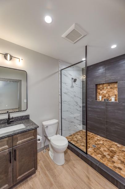 Full bath with charcoal large-format tile shower, amber hex mosaic pan and niche, and wood-look floor