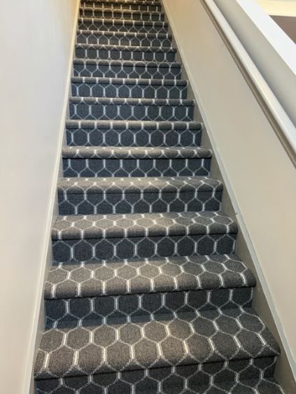 Charcoal honeycomb-pattern carpet installed on a straight staircase