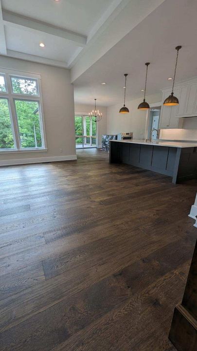 Open kitchen and living area with dark-stained wide plank oak hardwood flooring and slate blue island