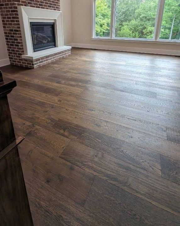 Dark character-grade oak hardwood flooring in a living room with brick fireplace