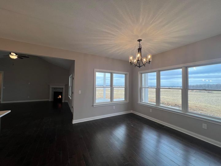 Espresso hardwood plank flooring in a dining room with chandelier, corner fireplace and prairie views