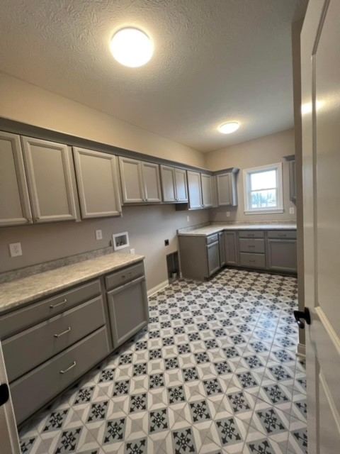 Gray and white patterned tile floor in a large laundry room with gray cabinetry