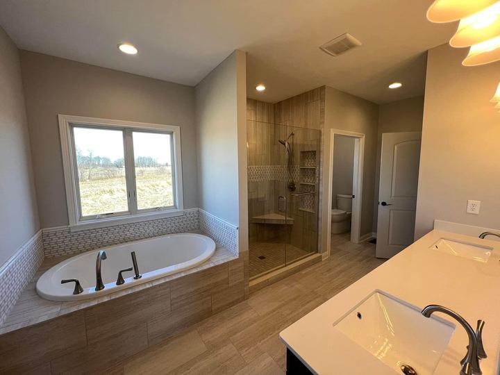 Master bathroom with mosaic-trimmed drop-in tub, tiled walk-in shower and wood-look tile floor