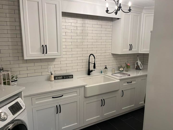 Laundry room with white subway tile wall, farmhouse sink, black faucet and charcoal plank tile floor