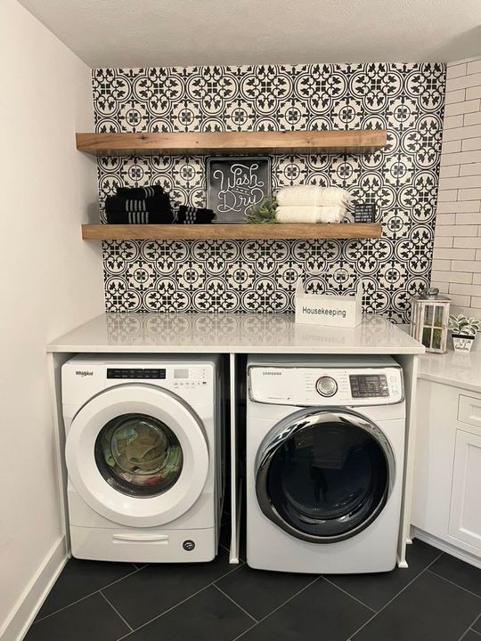 Laundry room with black and white patterned tile accent wall and dark slate-look tile floor
